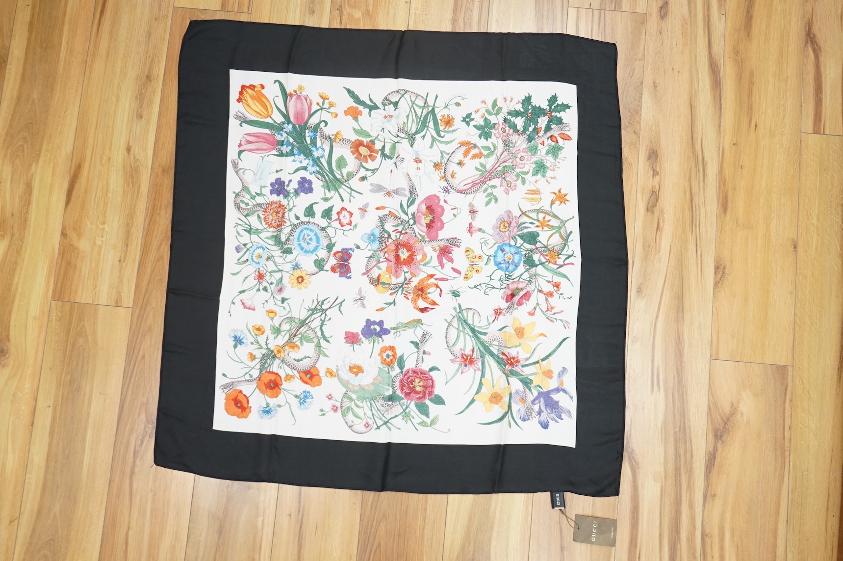 A Gucci floral silk scarf, with label and tag, a Gucci silk and net monogrammed scarf and a green & red monogrammed silk hair or bag ribbon